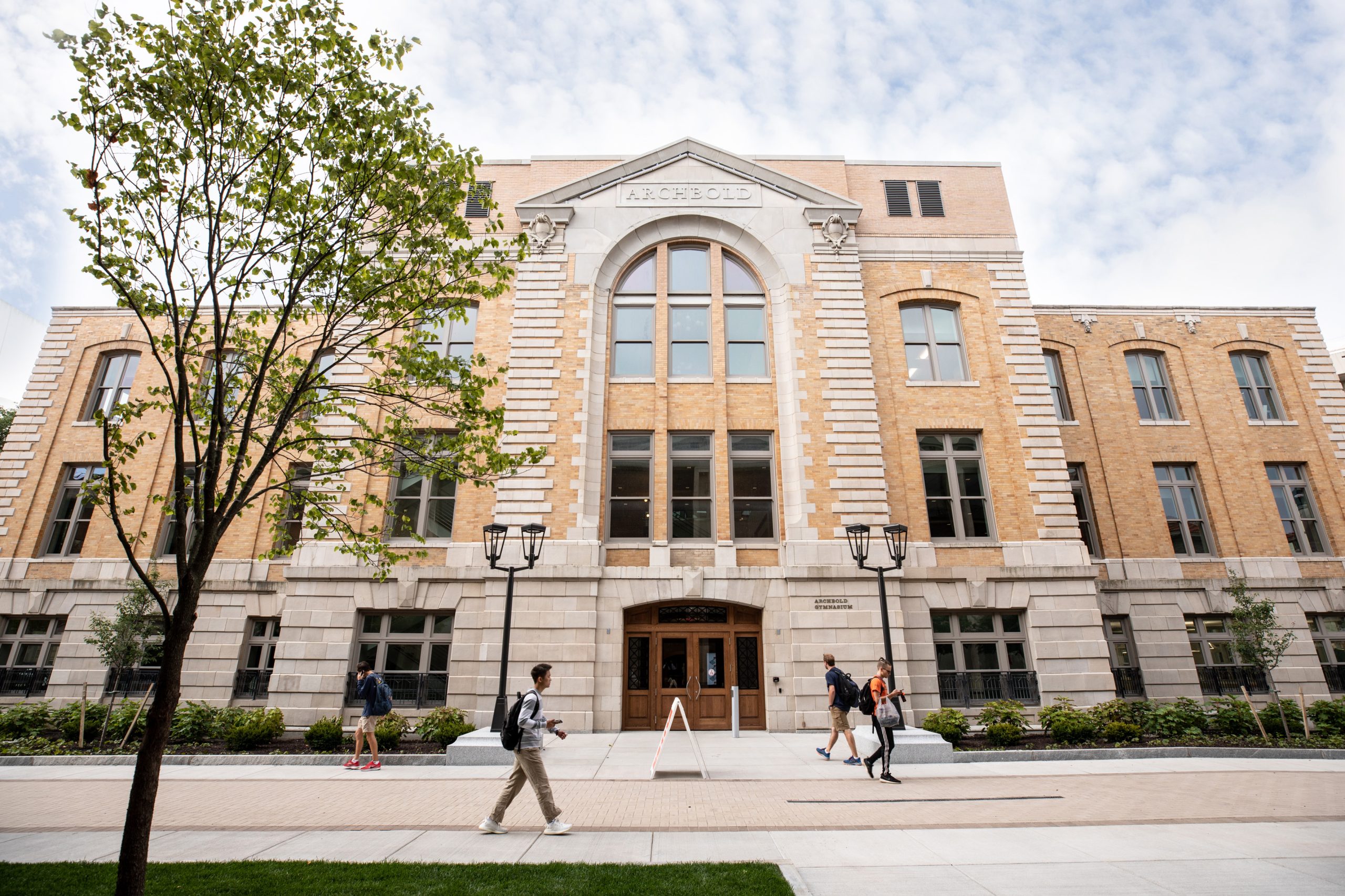 Students walk between Syracuse University Barnes Center at The Arch and Physics Building.