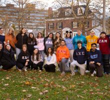 Students wearing shirts displaying Greek letters pose together in group