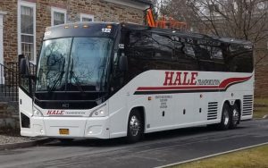 Hale Transportation coach bus outside of a building. The bus is white with red lettering that reads, 