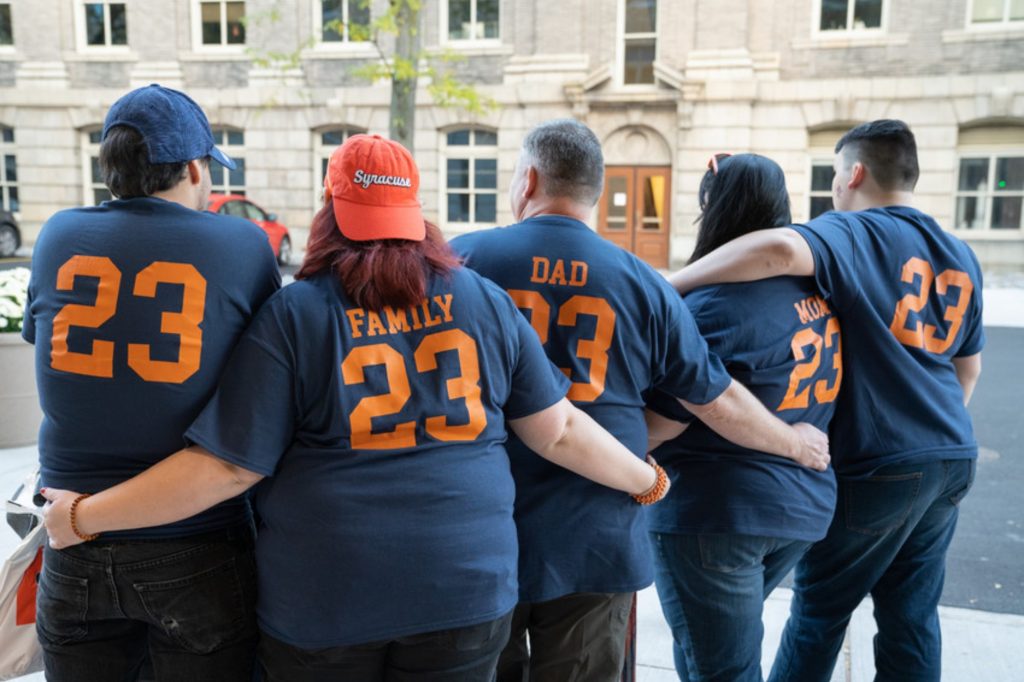 A Syracuse University family with matching team t-shirts facing away from the camera.