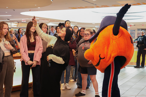 A student poses with Otto the Orange at Senior Celebration.