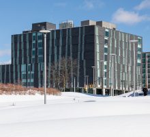 Image of Ernie Davis Hall surrounded by snow on a clear blue sky day.