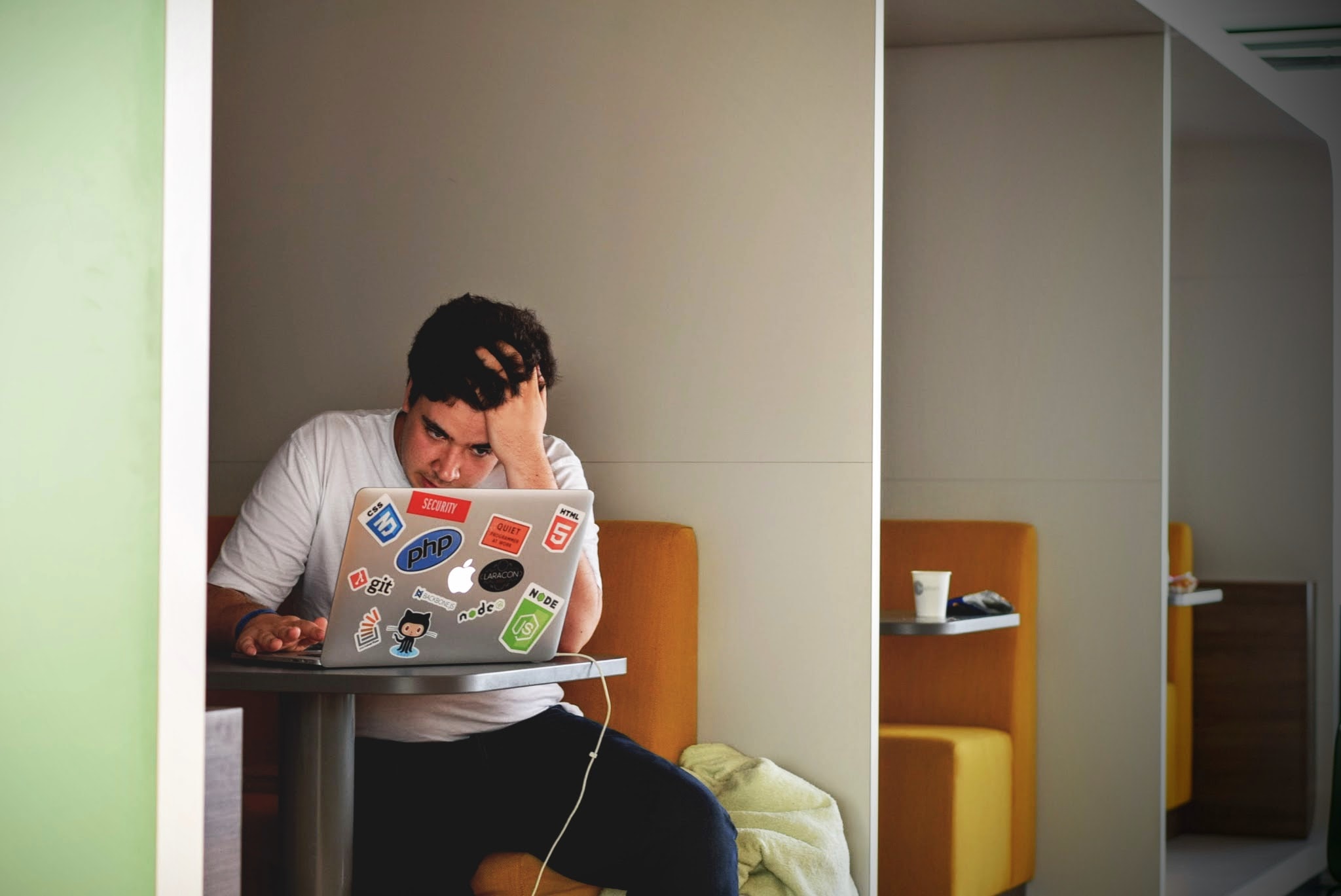 Man looks frustrated while on his laptop in a booth.