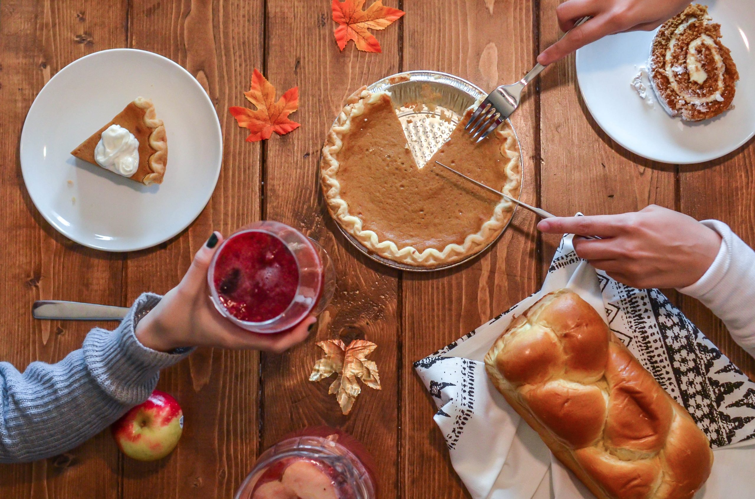 Someone slices pumpkin pie on a dining table