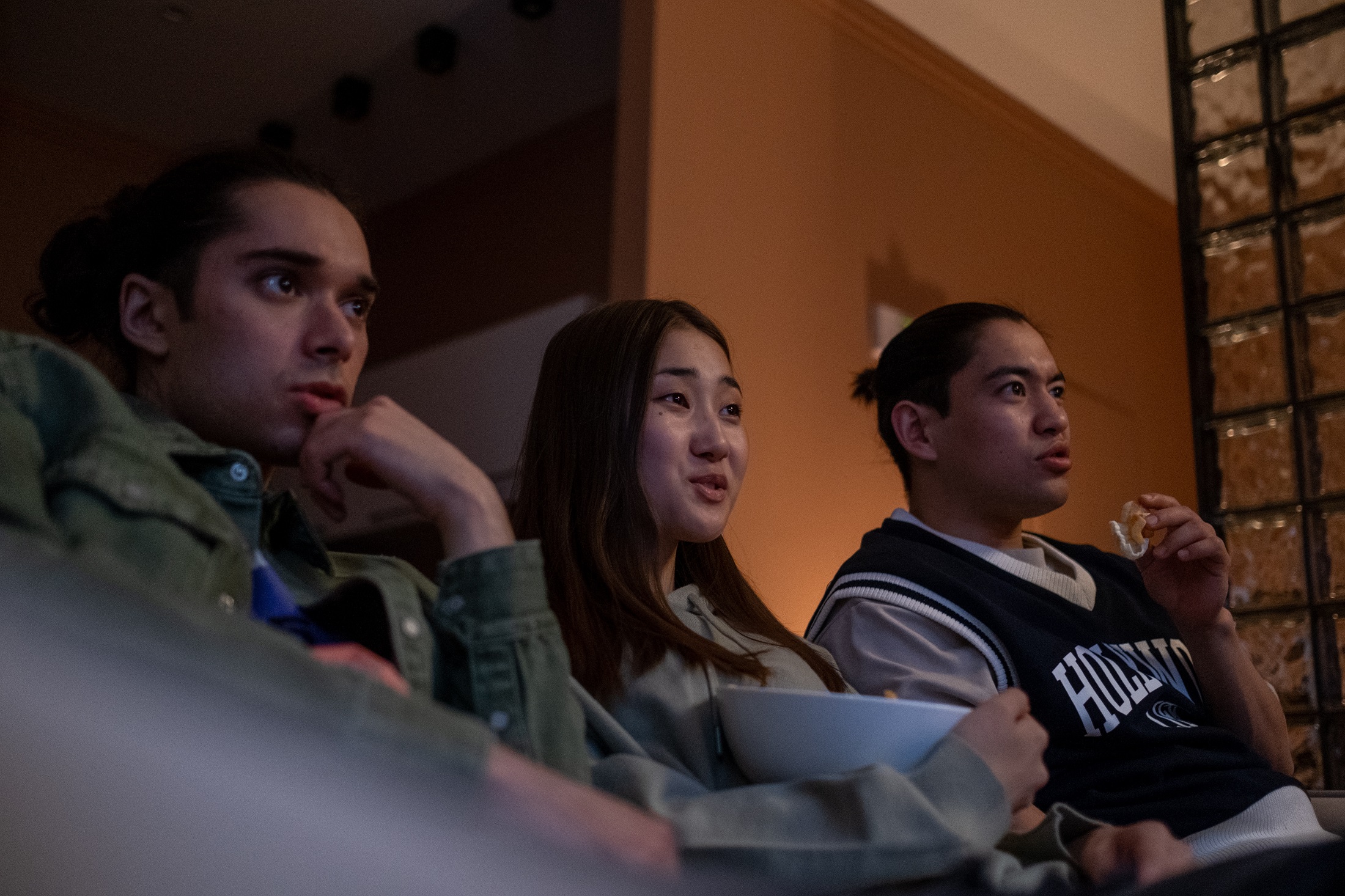 Three people sit on the couch watching TV