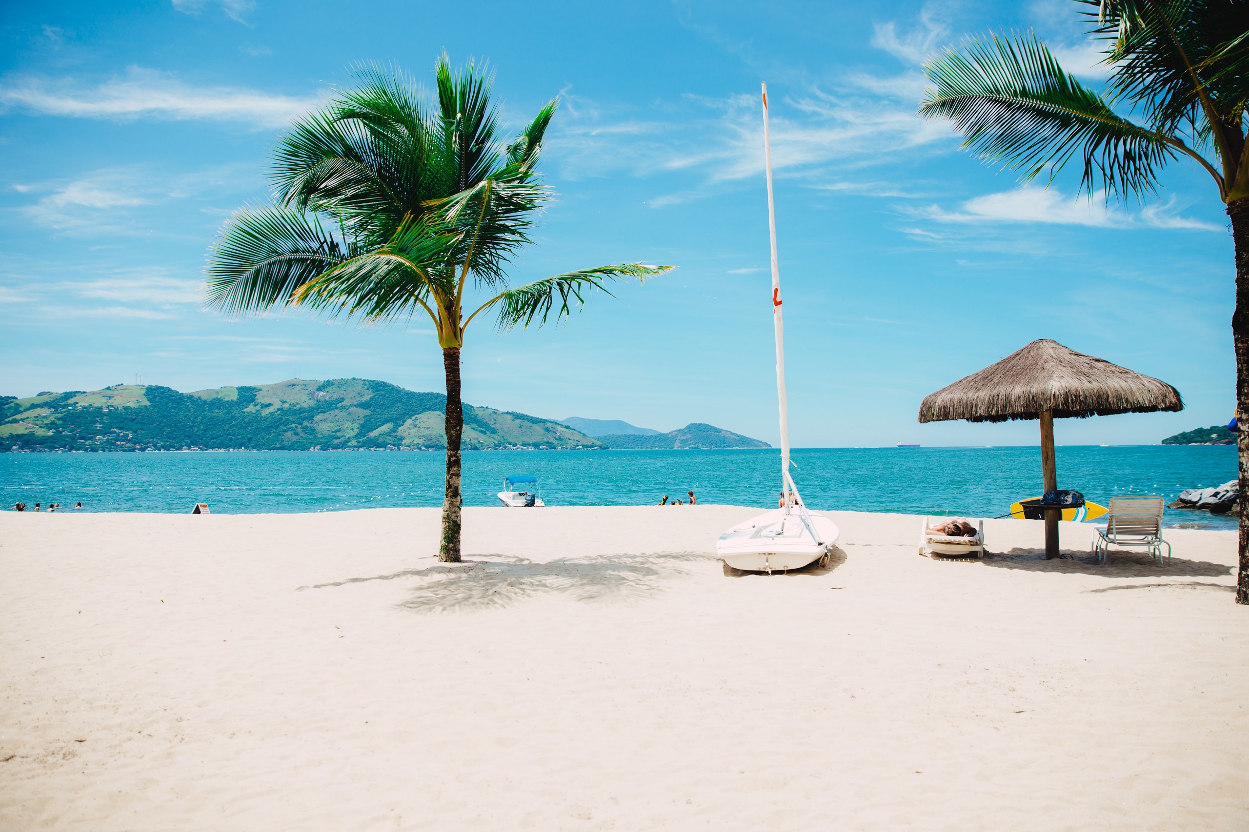 A white sandy beach with palm trees in front of a turquoise blue sea