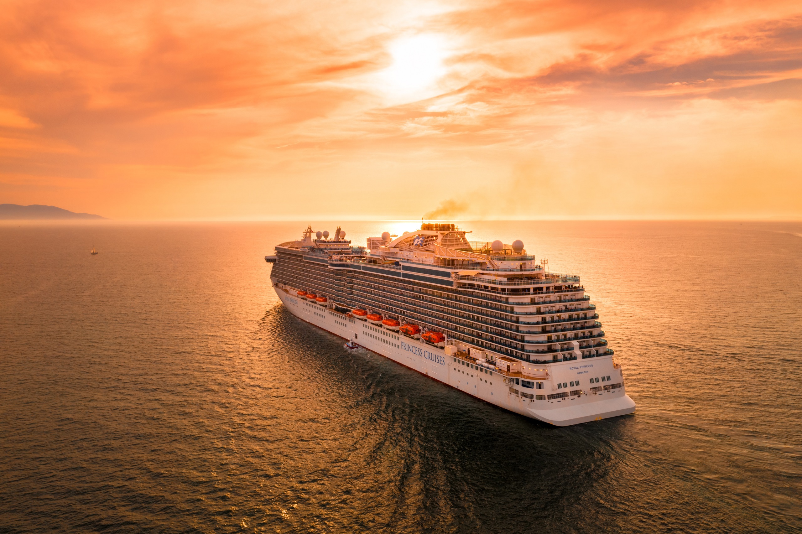 A cruise ships sails on the ocean at sunset