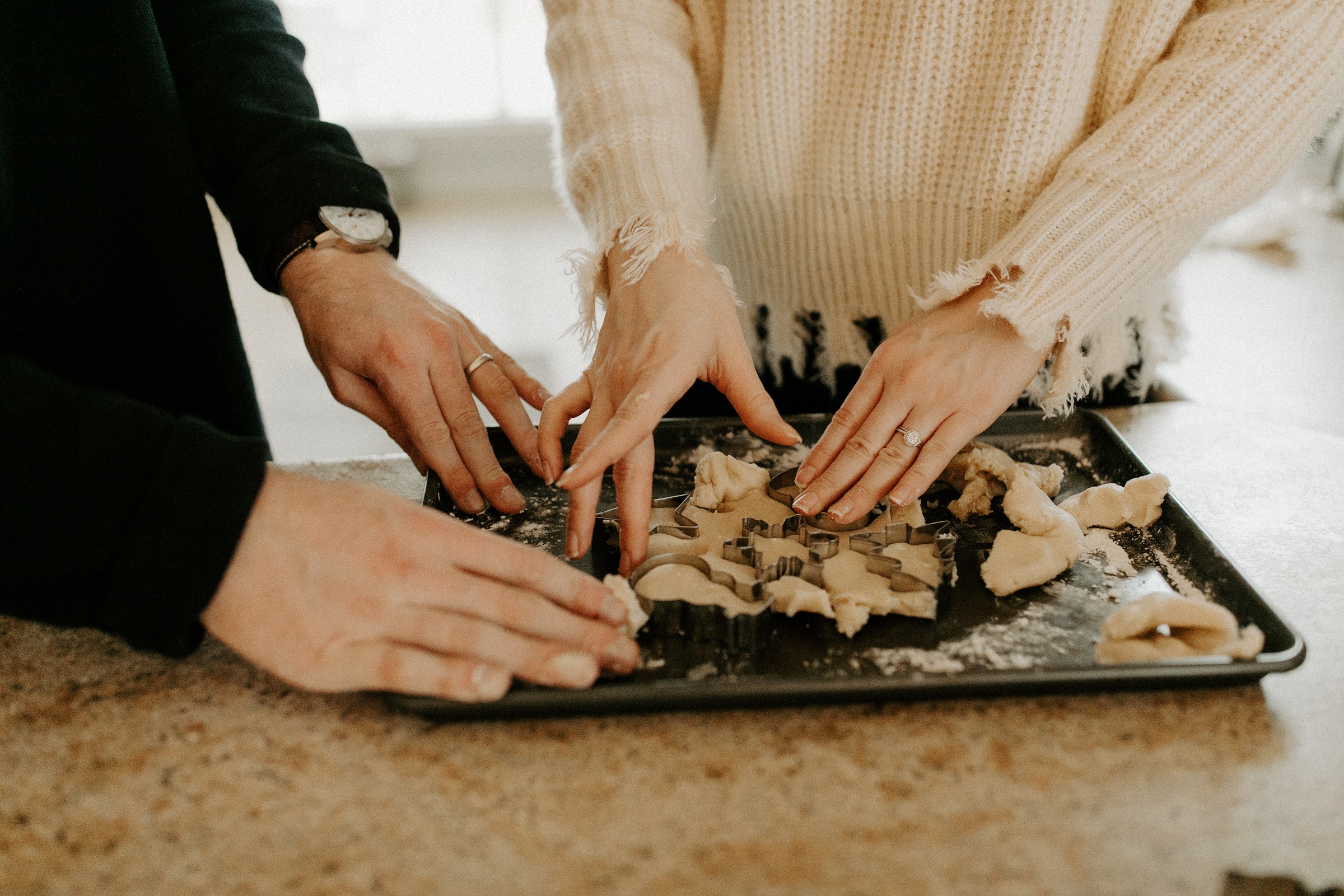 Two people make cut-out holiday cookies.