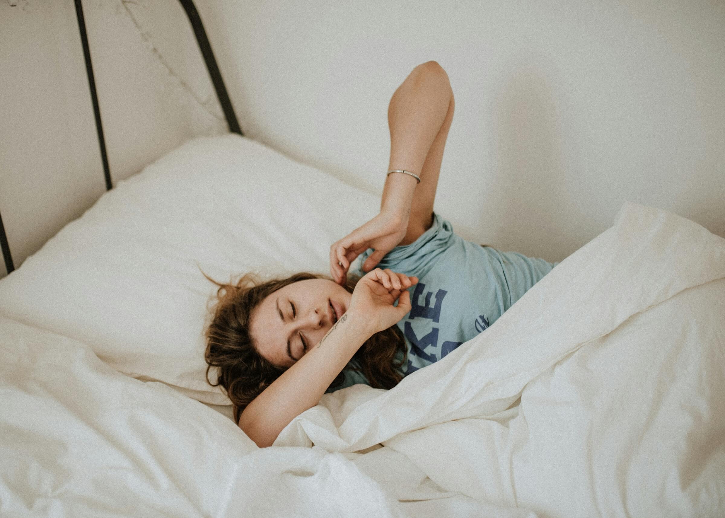 Woman stretches in bed after waking up in the morning.