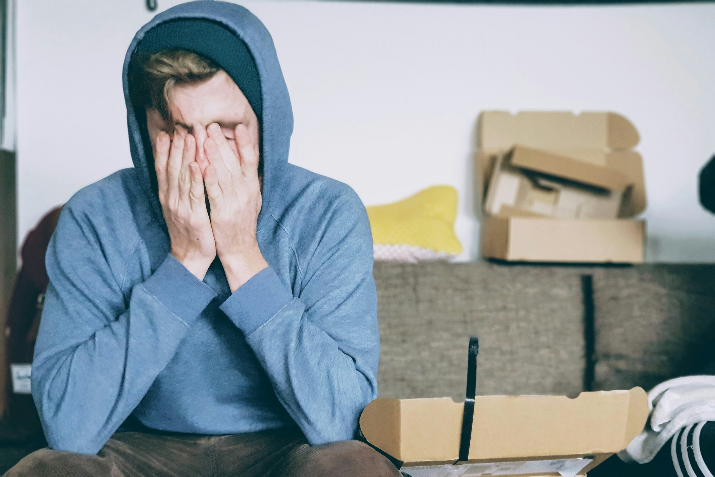 Person sitting on a couch with their hands over their face.