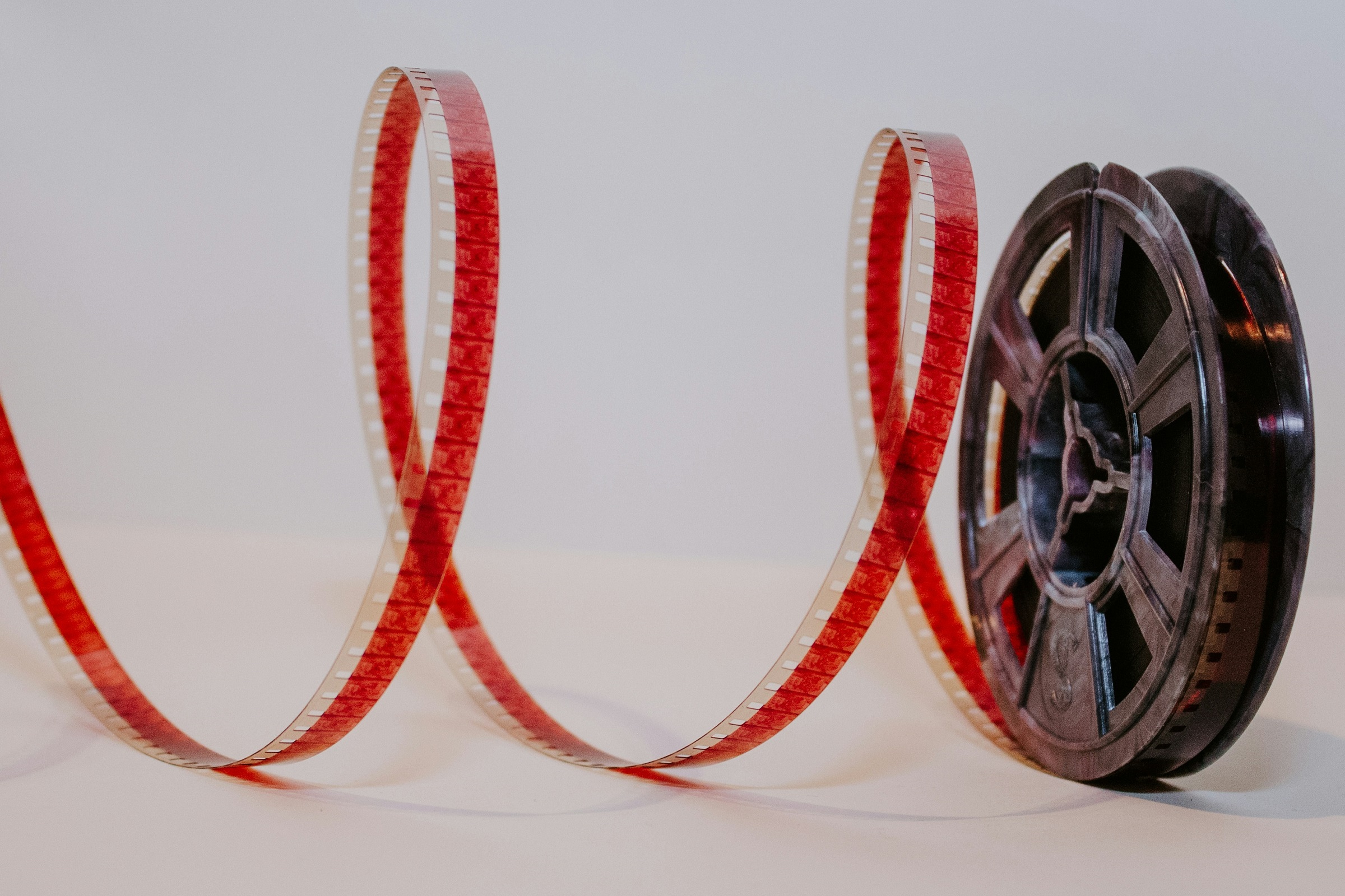 A film reel with red film trailing out of it.
