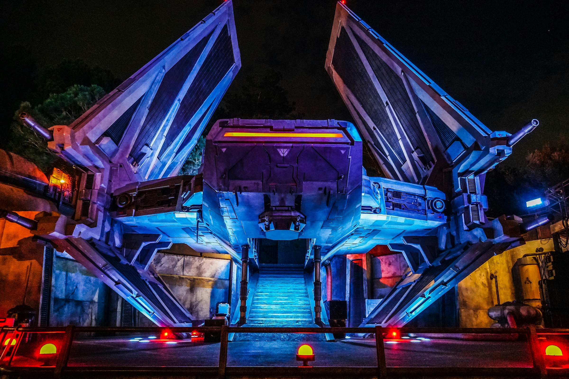 A sci-fi spaceship at night, lit by blue and yellow lights.