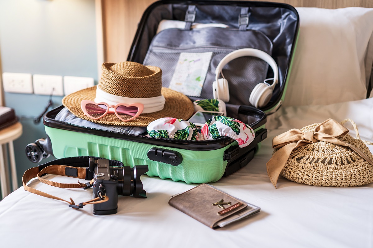 Traveler suitcase and luggage with travel accessories neatly packed but open on a bed.