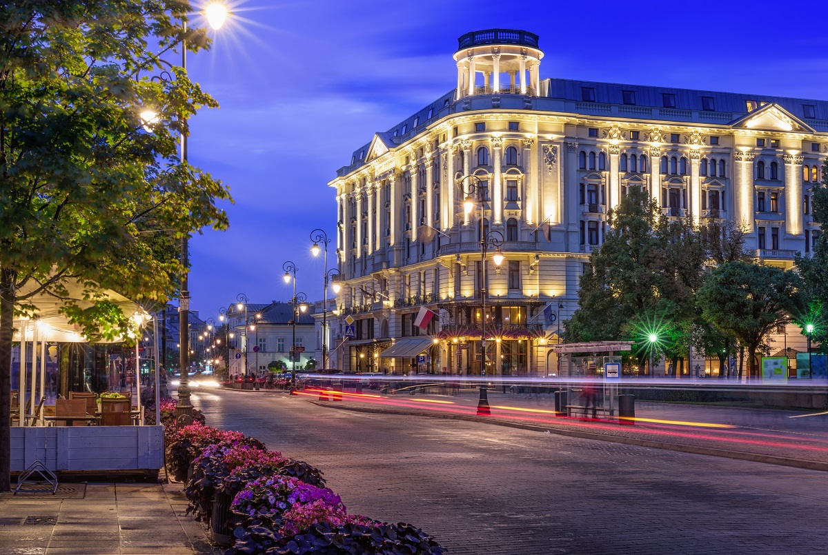 A fancy hotel lit up on a city street at dusk.