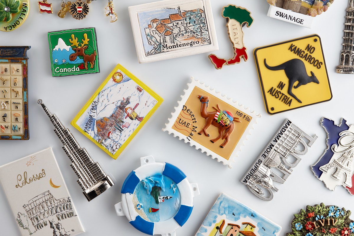 Magnet souvenirs from all around the world on white refrigerator.
