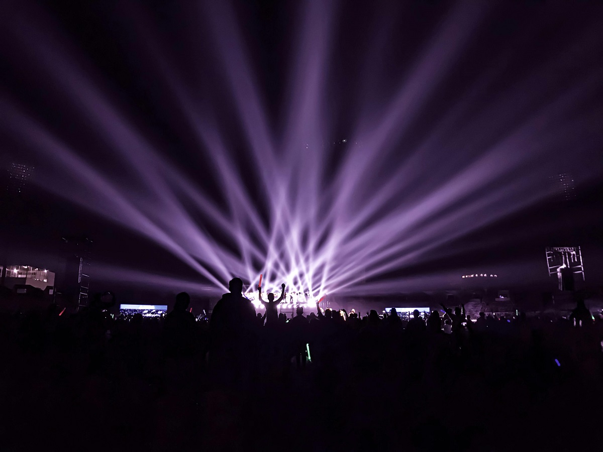 Purple concert lights shine over a concert crowd
