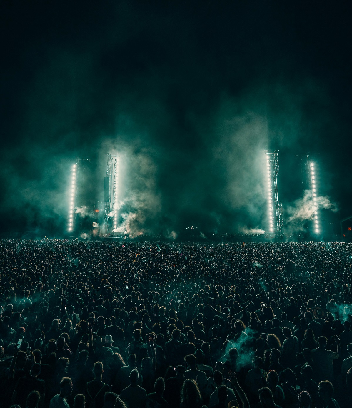 Greenish lights on a concert stage illuminating a concert crowd