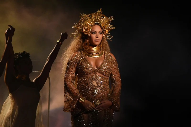 Beyonce dressed in a beaded gold gown and a gold crown