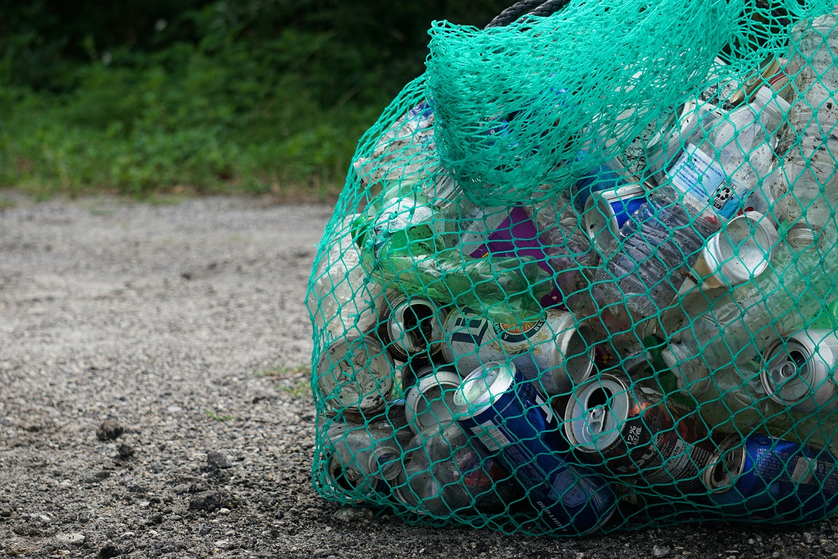 A netted bag of collected bottles and cans on a road