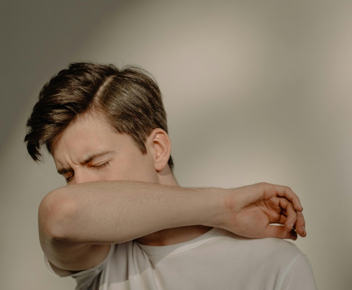 A man sneezing into his elbow