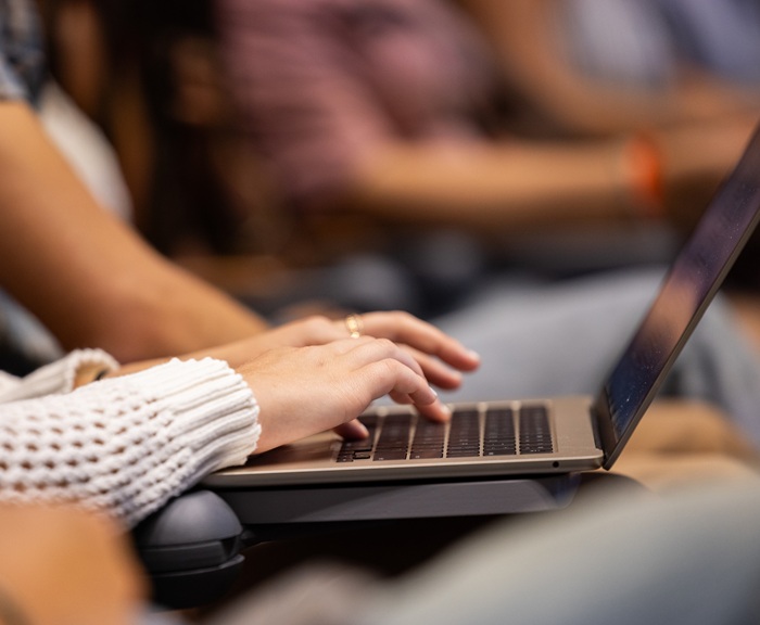 A student uses a laptop in a lecture hall.