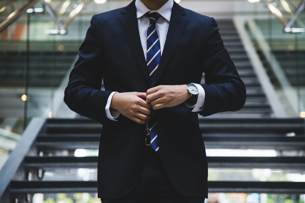 A man in a suit standing on a modern-looking staircase.