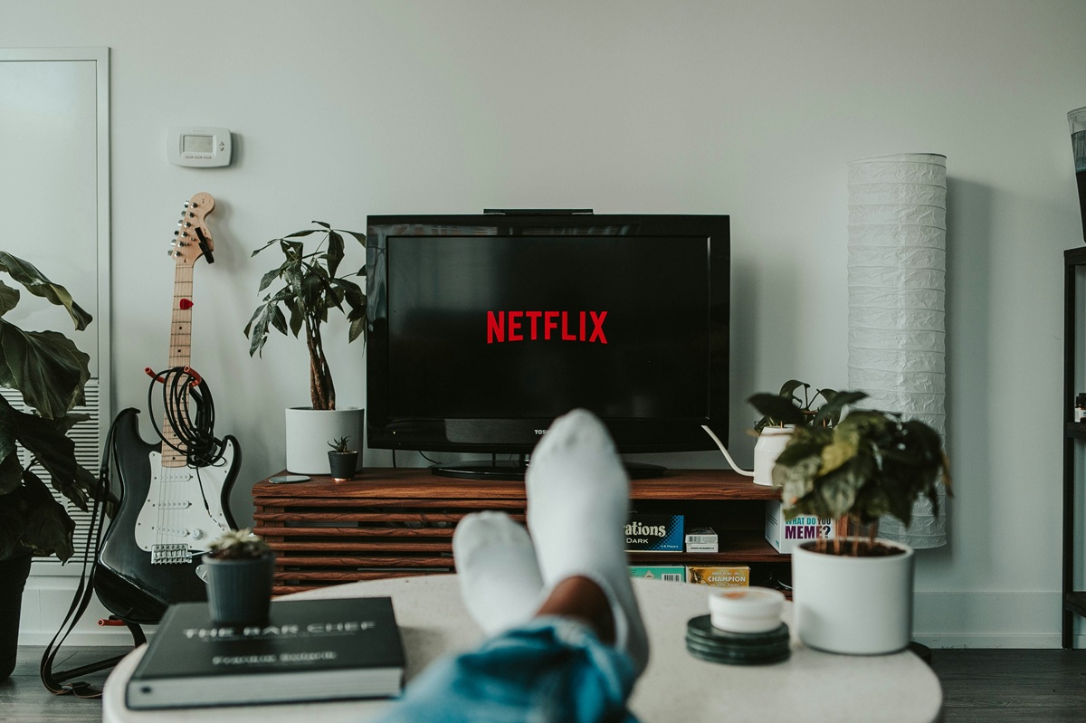 A person's feet are propped up on their coffee table as Netflix boots up on their TV.