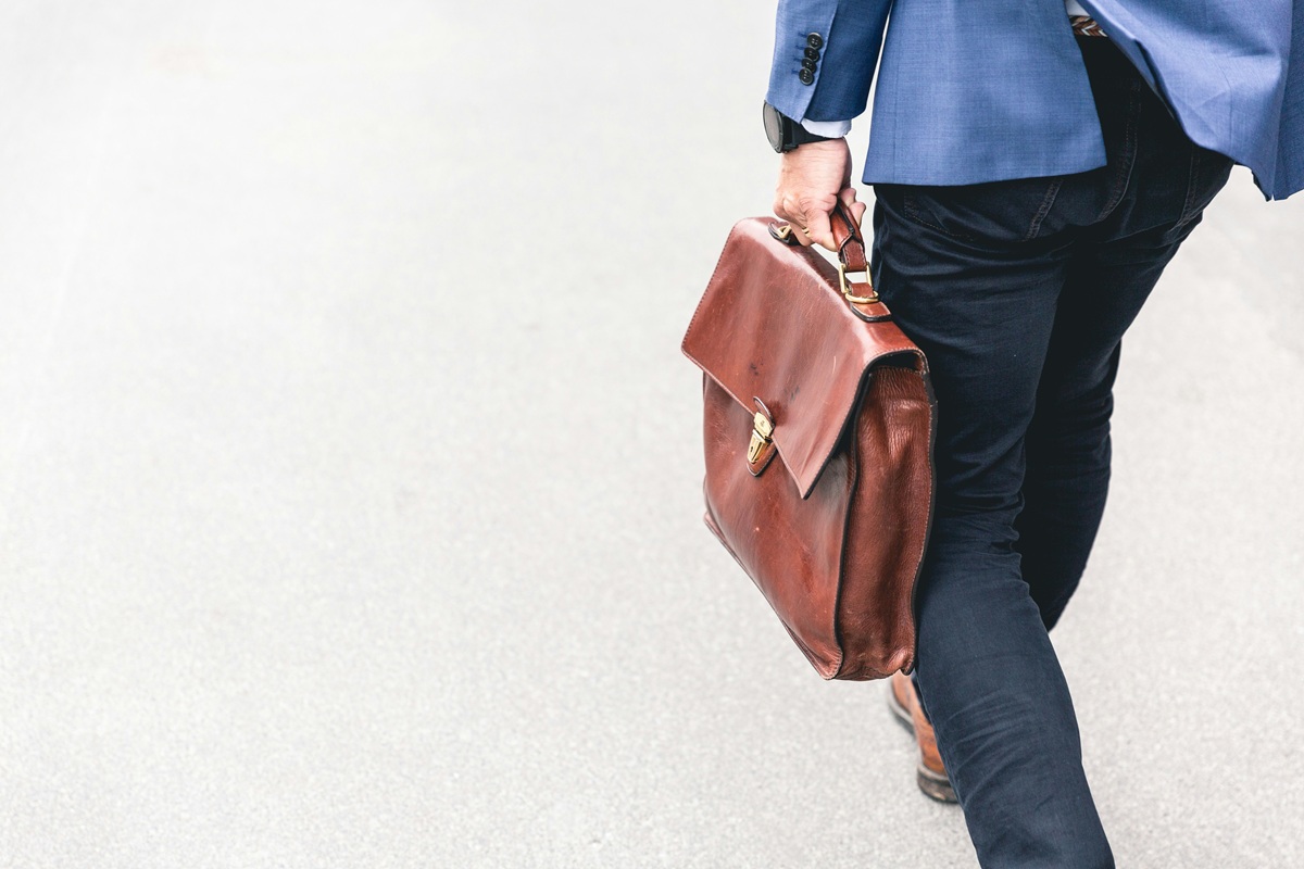 a person holding a brown briefcase style bag