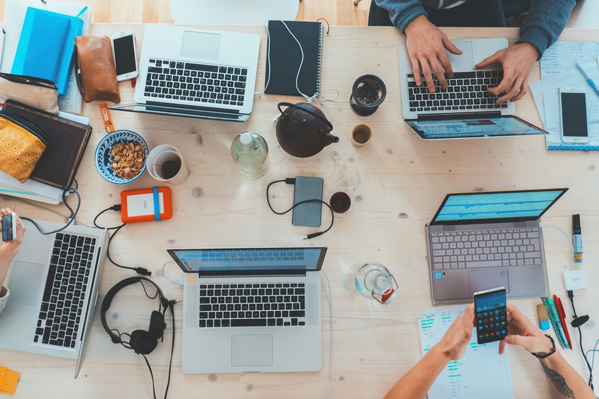multiple people working on their laptops on a shared table