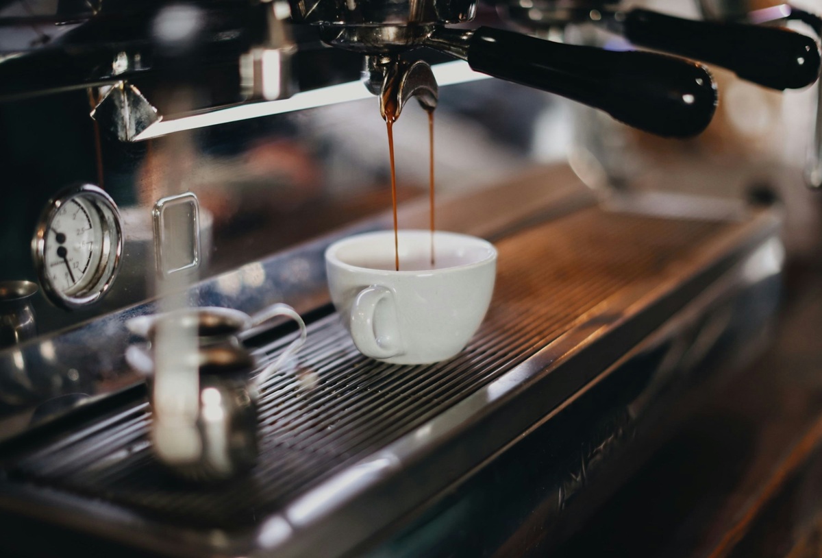 a shot of espresso being extracted by a machine into a white mug