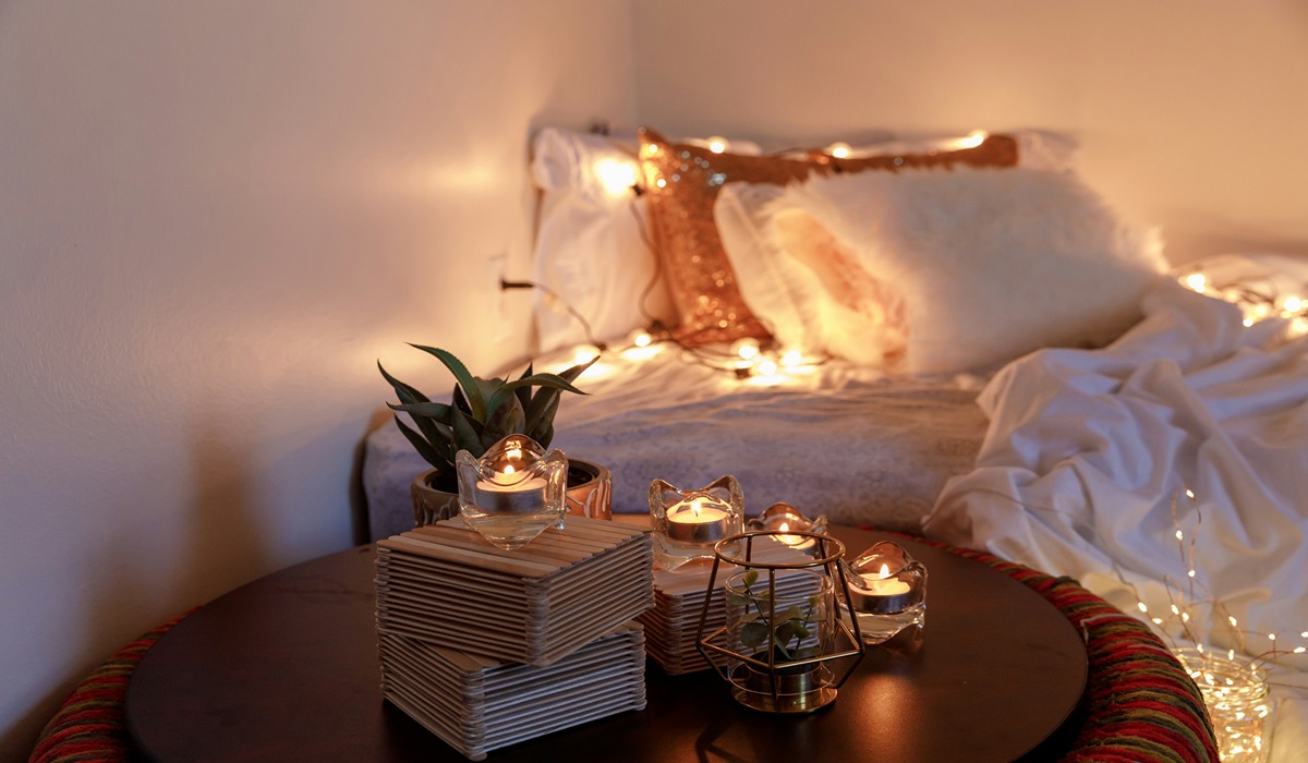 Bed surrounded by lights and a nightstand with candles on it