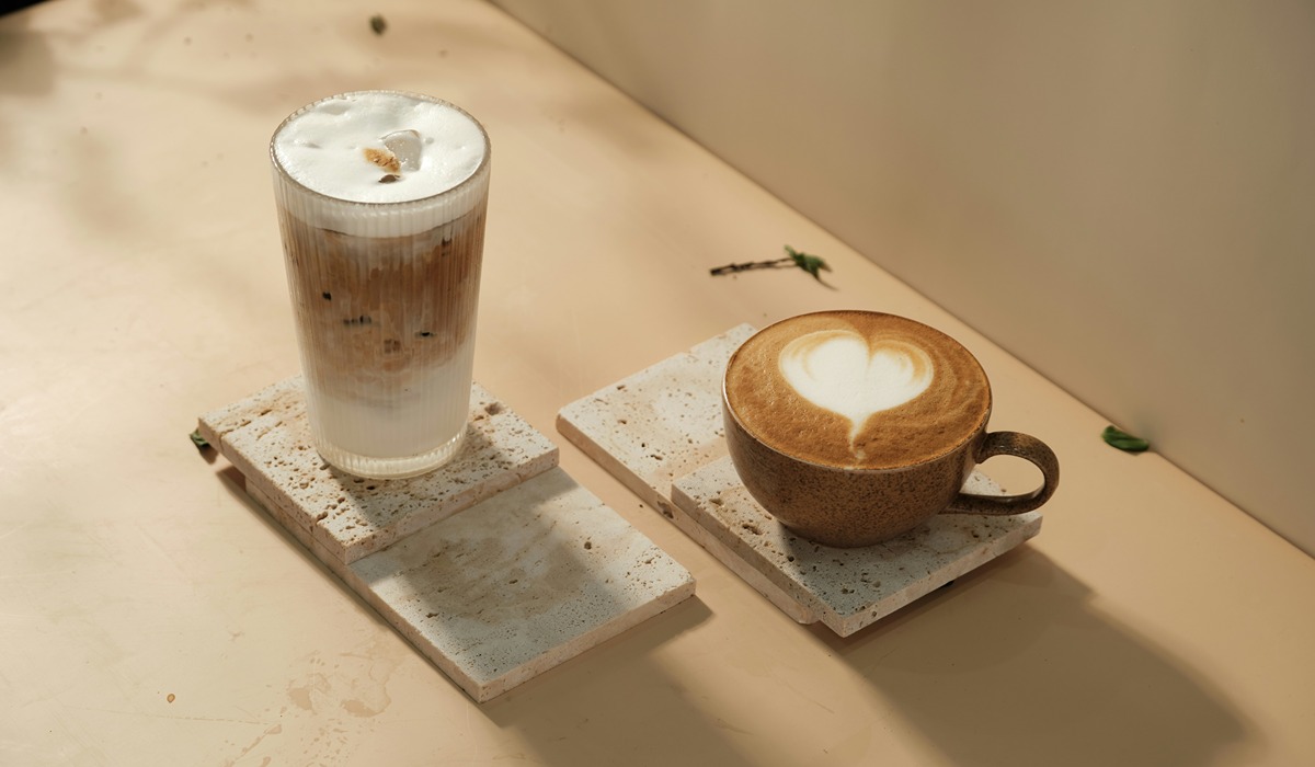 Two lattes side by side, one cold and one hot on a wooden tray