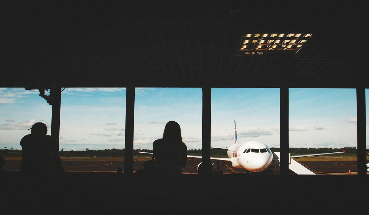Two people staring at an airplane at a airport in shadow