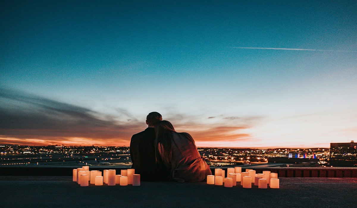 A couple watching a sunset with candles circling them