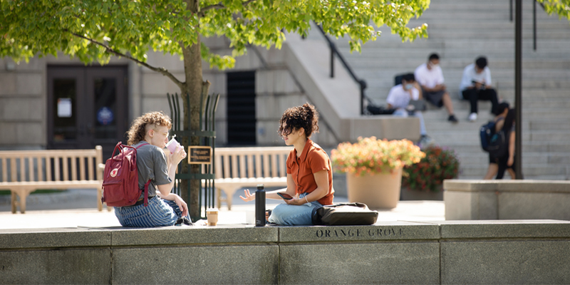 Students speaking on a bench in front of the Hendricks Chapel stairs.