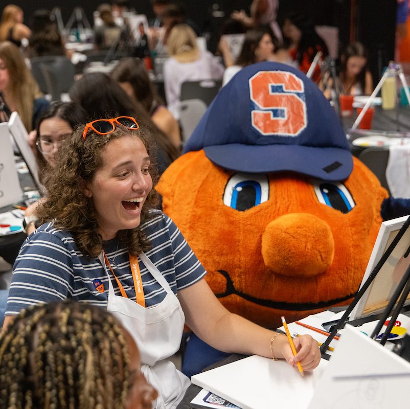 Students and Otto the Orange participate in a painting activity